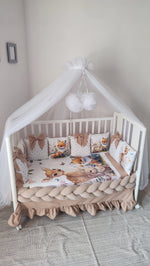Set lettino neonato beige con paracolpi a treccia, cuscini a fiocco tema bosco e baldacchino in tulle bianco
