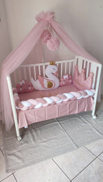 Set lettino neonata rosa con baldacchino in tulle, paracolpi a treccia e cuscini decorativi a forma di cigno e corona.