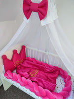 Set culla fucsia con paracolpi a treccia, cuscino corona, riduttore babynest, lenzuolo a cuori e baldacchino con fiocco.