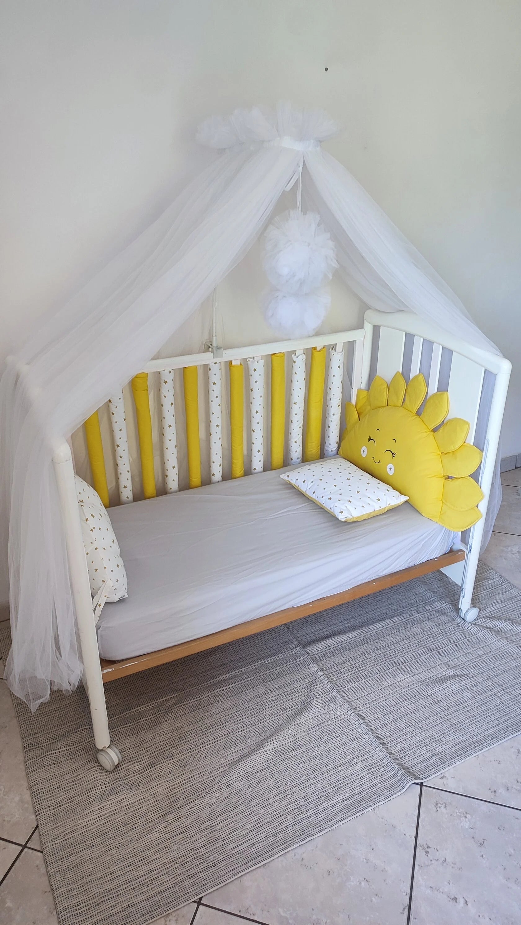 Set paracolpi americani gialli con stelle dorate per lettino neonato, abbinati a baldacchino in tulle bianco e cuscino sole, cameretta bambino