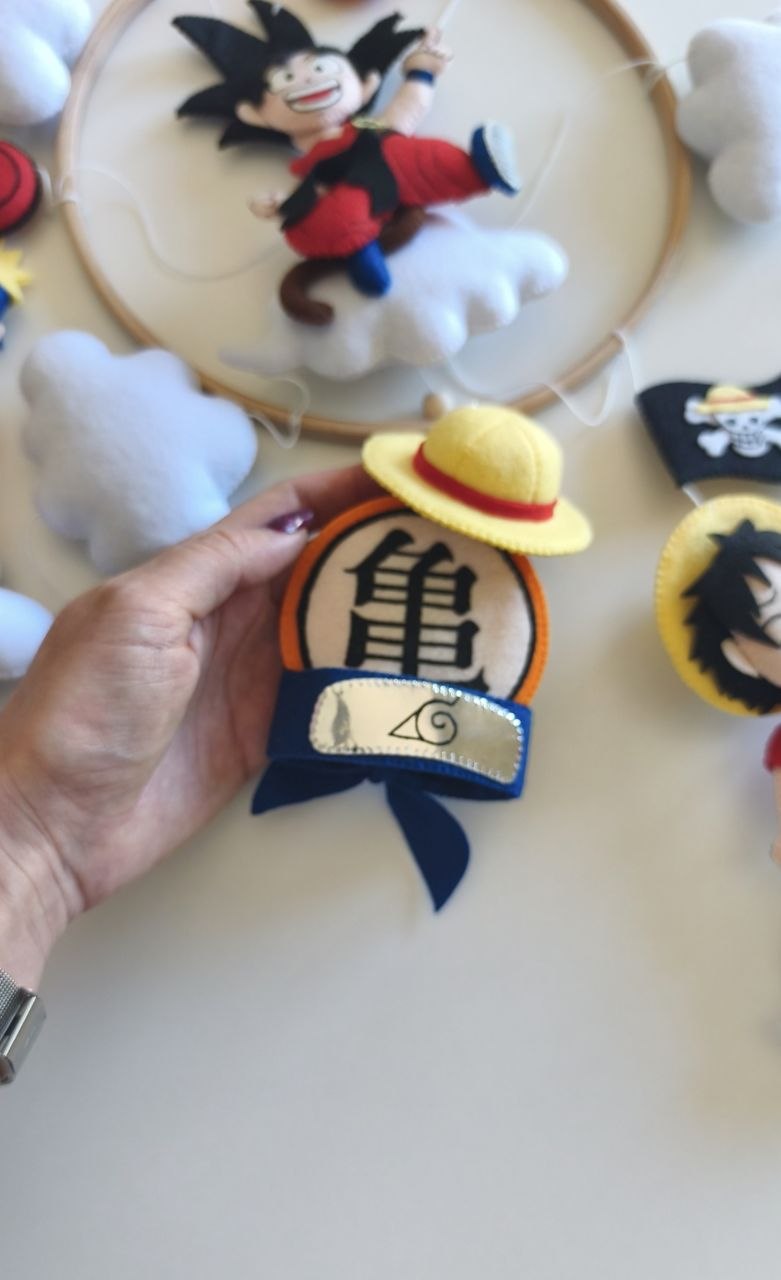 Simboli anime in feltro: cappello di paglia, emblema della tartaruga e fascia ninja, dettagli della giostrina