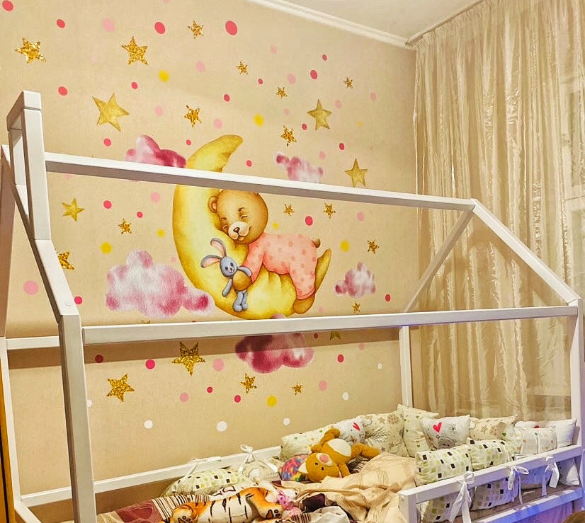 Decorazioni adesive da parete per bambini con grande orso di peluche su una luna gialla, nuvole rosa e stelline dorate lucide.