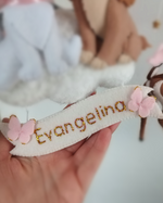 Dettaglio targhetta in feltro con nome ricamato glitter e farfalle rosa, giostrina neonata