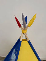 Dettaglio piume tenda teepee bambini in rosso, grigio, blu e giallo, pali legno naturale e decorazione artigianale