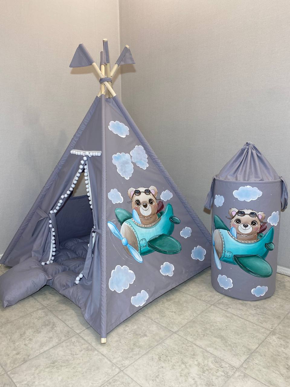 Tenda tipi bambini grigia con orsetto aviatore su aereo dipinto a mano, nuvole, pompon bianchi e cestino coordinato