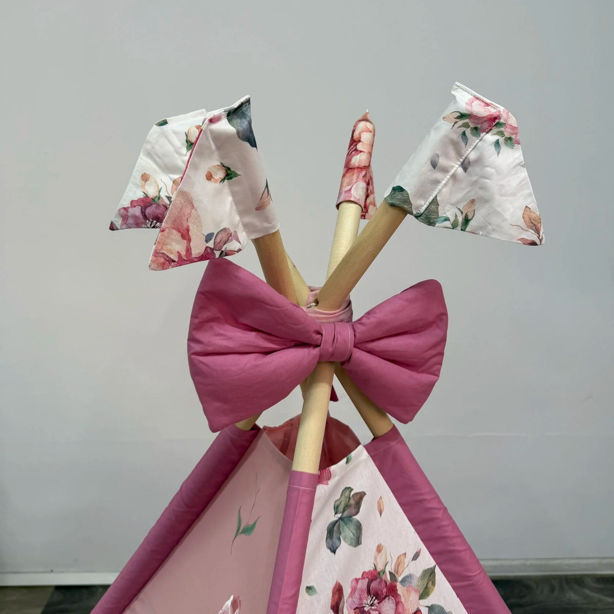 Tenda teepee bambini vista dall’alto con pali in legno, fiocco rosa e decorazioni floreali – idea regalo bambina