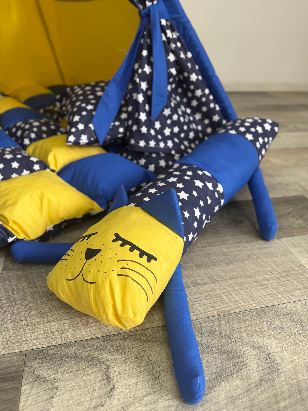 Tenda teepee bambini vista interna con tappeto blu e giallo a scacchi, stelline e cuscino a forma di gatto coordinati