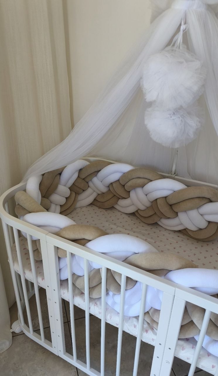 Treccia paracolpi a 8 fili beige e bianco su lettino ovale bianco con velo baldacchino in tulle