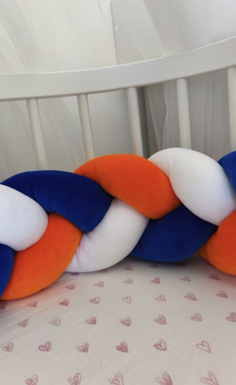 Treccia paracolpi blu royal, arancione e bianco montata lungo le sponde del lettino