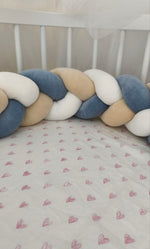 Dettaglio della treccia paracolpi blu polvere, beige e bianco fissata alle sbarre del lettino