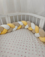 Treccia paracolpi giallo, beige e bianco montata lungo le sponde arrotondate di un lettino ovale