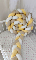 Treccia paracolpi a 3 fili giallo sole, beige classico e bianco in velluto, avvolta dentro un lettino ovale bianco