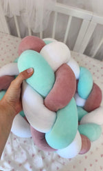 Mano che tiene la treccia paracolpi a 3 fili menta, rosa antico e bianco in velluto, dettaglio dell'intreccio morbido