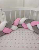 Treccia paracolpi rosa baby, grigio classico e bianco montata intorno al lettino con lenzuolo a cuoricini