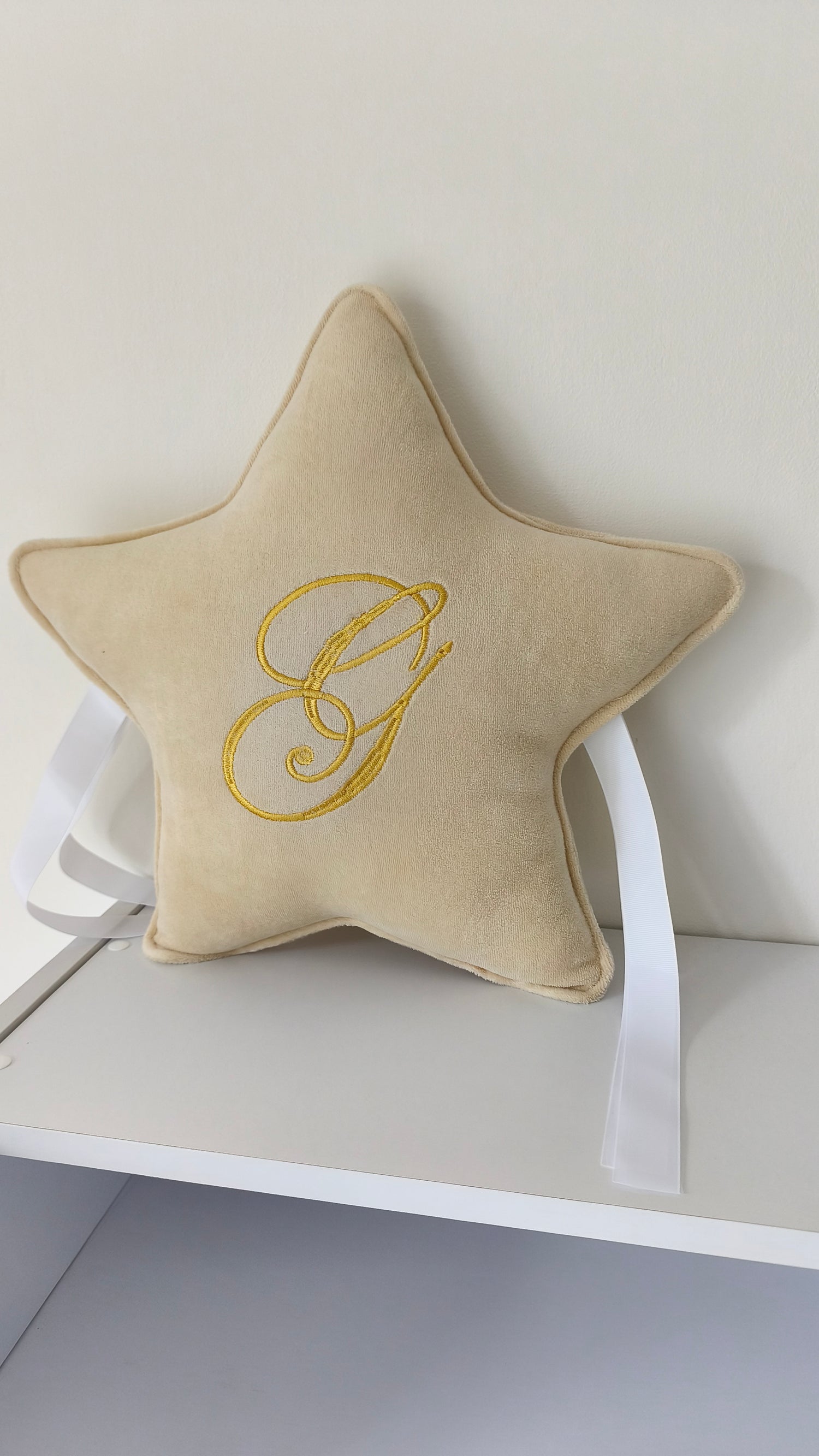 Cuscino stellina velluto beige con lettera G ricamata oro e nastri bianchi per lettino cameretta neonato