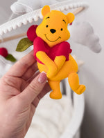Winnie the Pooh in feltro cucito a mano per giostrina musicale culla, dettaglio personaggio con maglia rossa e nuvole.